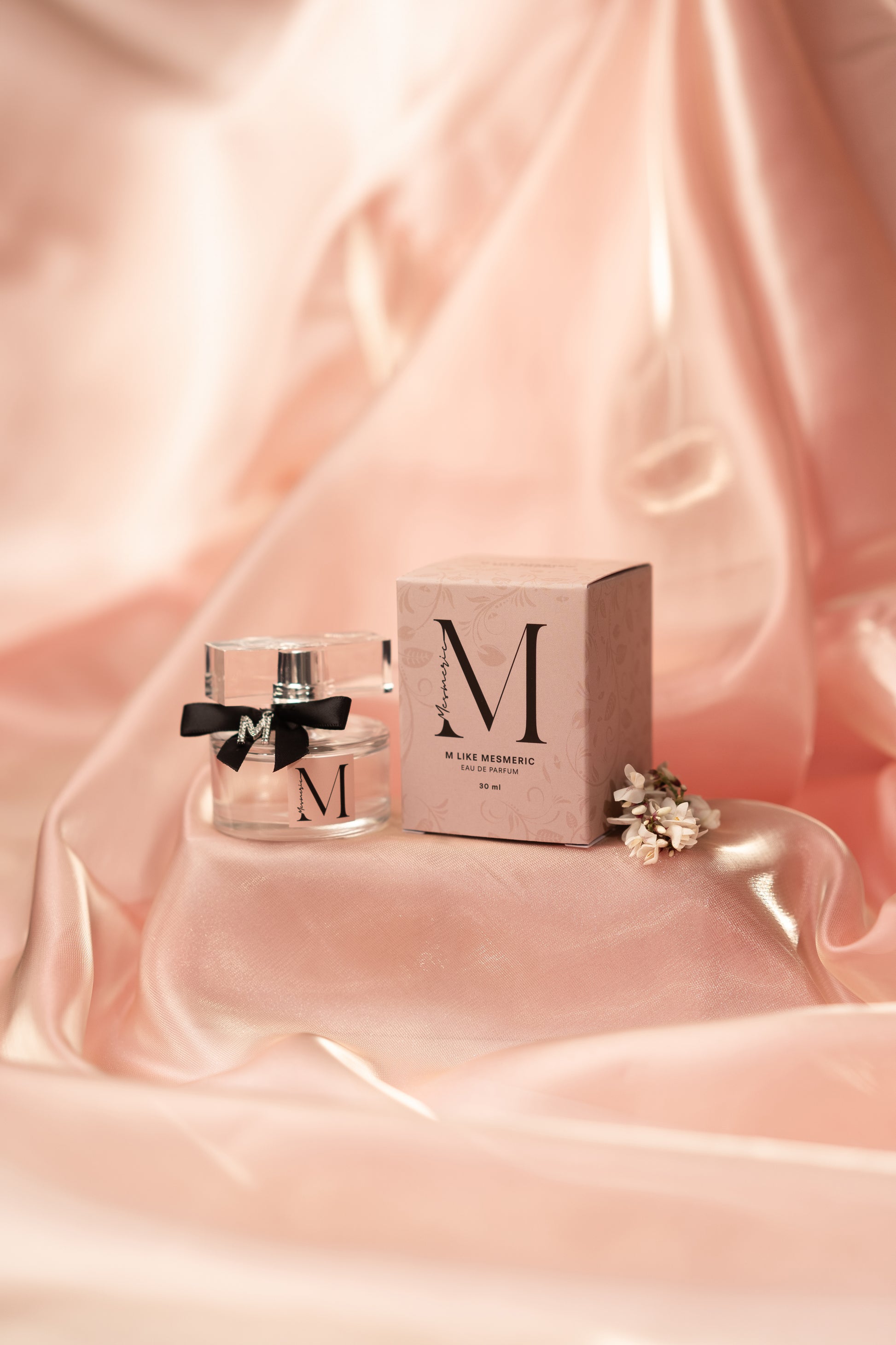 A bottle of parfum with its box on powder colored silk satin backround